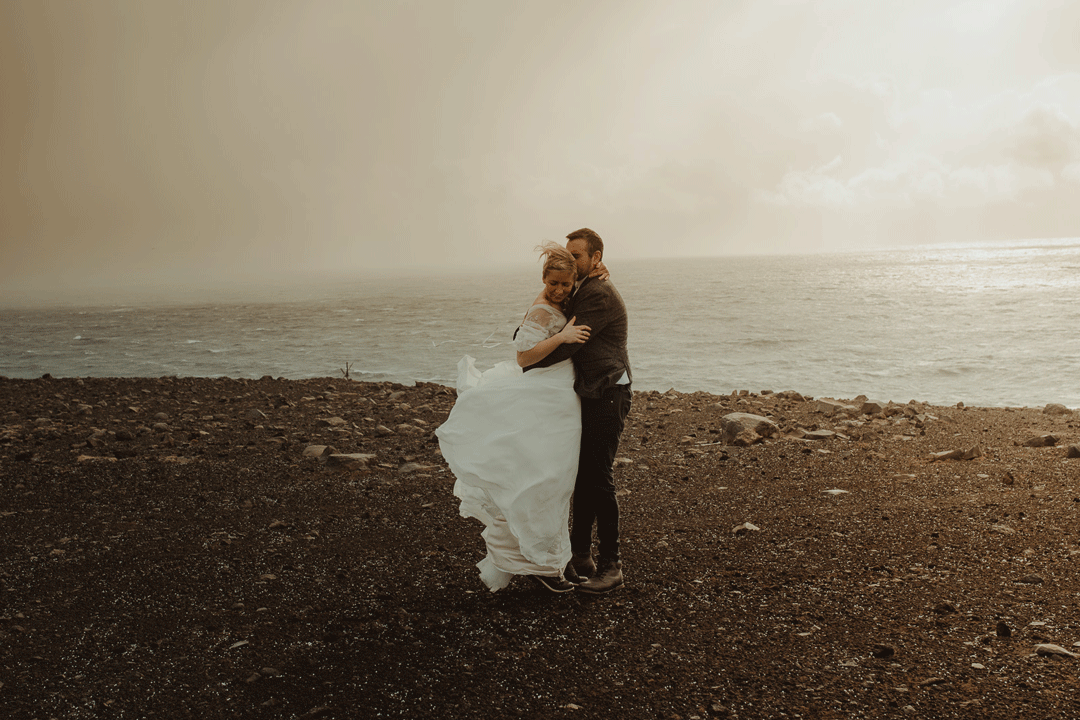 Couple in a wind in iceland on a cliff edge
