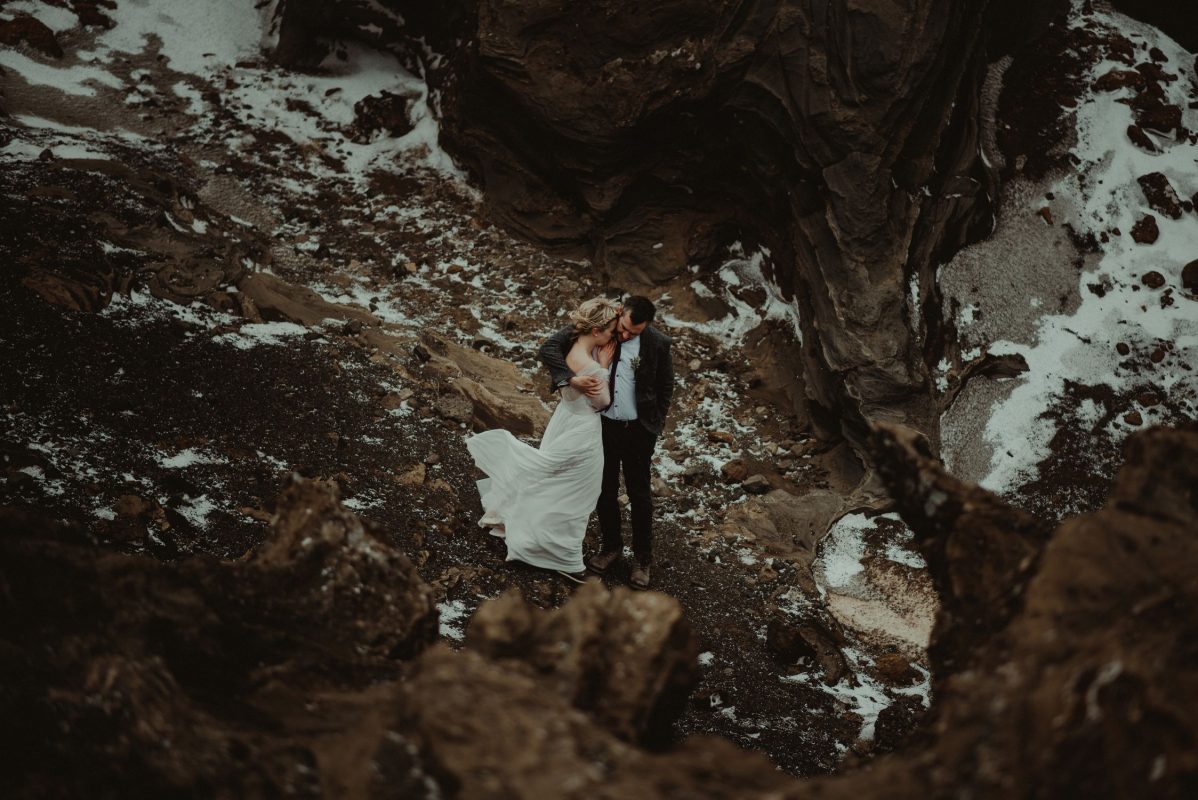 Iceland wedding portrait of a couple warming up by rocks