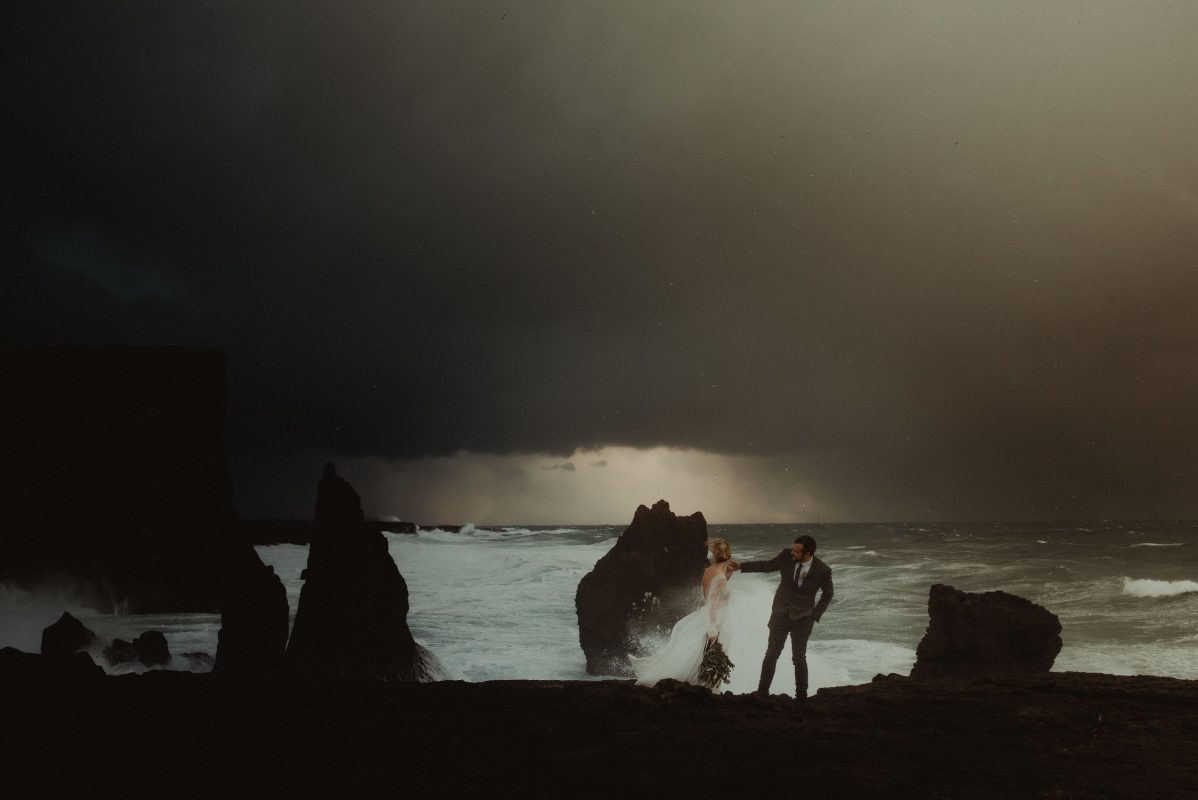 Dramatic Iceland wedding portrait of a couple posing by the waves