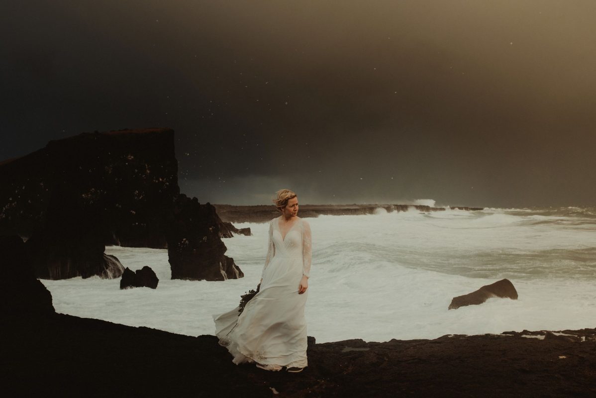 Dramatic Iceland wedding portrait of a bride posing by the waves